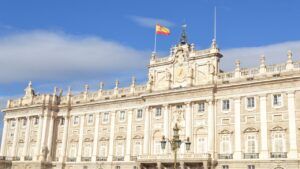 Fachada monumental de un palacio histórico con bandera española, evocando 10 lugares turisticos alcala henares