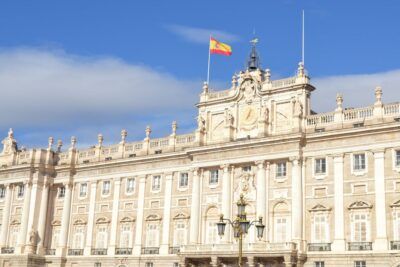 Fachada monumental de un palacio histórico con bandera española, evocando 10 lugares turisticos alcala henares