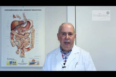 Médico con bata blanca y micrófono junto a un póster del aparato digestivo explicando conceptos 2TBDWEqB2TA.