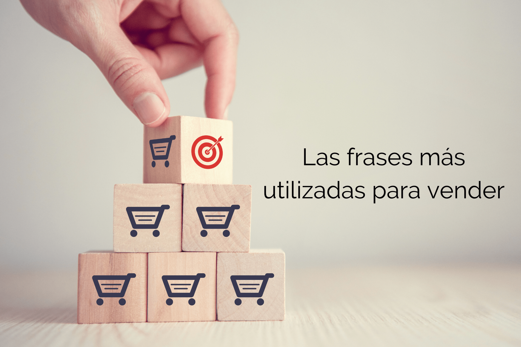 Mano colocando un bloque con diana sobre una pirámide de cubos con iconos de carrito, simbolizando 7 pasos para utilizar la ley de atraccion y recuperar a tu ex.