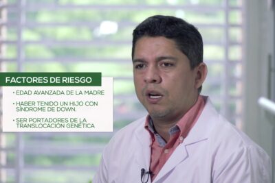 Médico con bata blanca y micrófono junto a un recuadro que enumera factores de riesgo para síndrome de Down 9JdVUDYiSL0.
