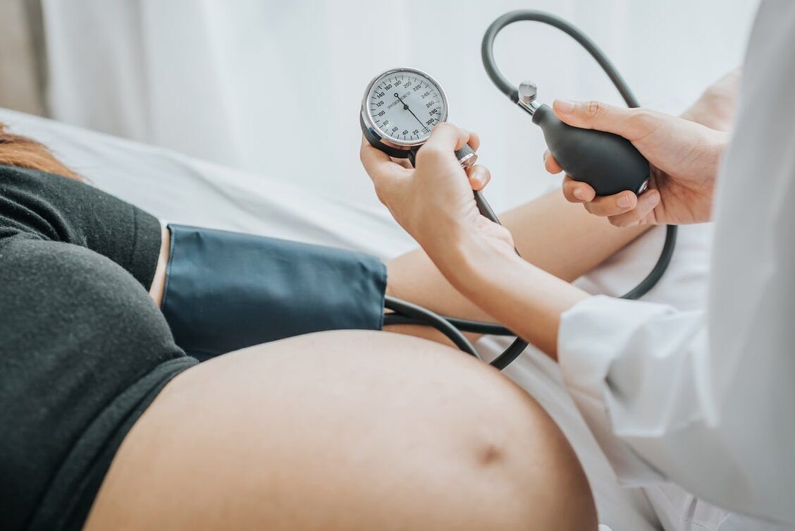 Paciente embarazada recibiendo toma de presión arterial mientras consulta sobre abortar en el primer mes de embarazo cuales son las consecuencias 1
