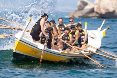 Remeros sincronizados en una embarcación amarilla remando con fuerza y salpicaduras, actividades deportivas arganda rey practicar.