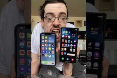 Persona sosteniendo dos teléfonos móviles con las pantallas de inicio visibles en una comparativa android iphone