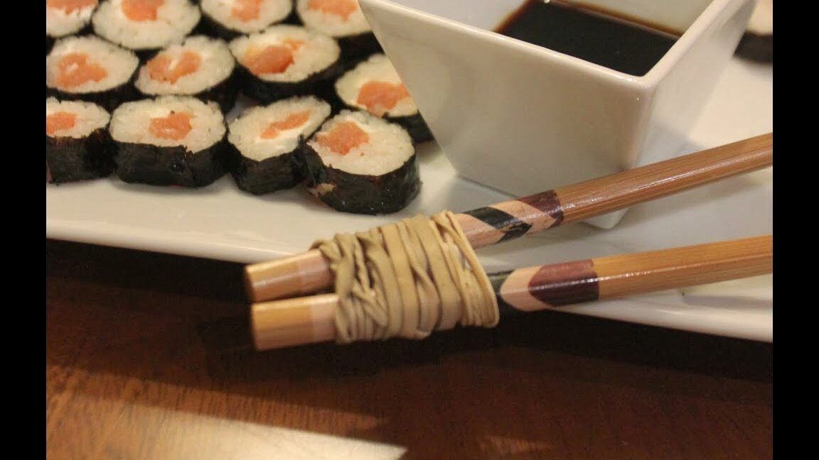 Aprende a usar palillos chinos al estilo kimetsu no yaiba 1 mostrando palillos de madera unidos con una goma junto a rollos de sushi y salsa
