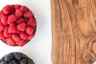Boles de frambuesas y moras junto a una tabla de madera, aprende preparar delicioso aji gallina
