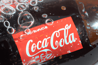 Botella de Coca-Cola de vidrio con etiqueta roja y burbujas, recurso visual sobre coca cola caducada es seguro consumirla