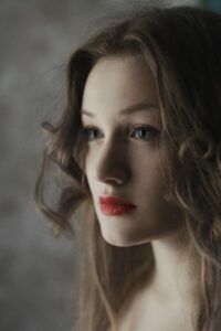 Retrato íntimo de una mujer con mirada suave y labios rojos que ilustra como romper hielo descubre tecnicas efectivas mediante contacto visual y lenguaje corporal.