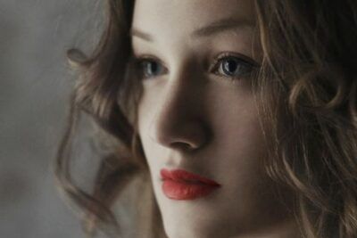 Retrato íntimo de una mujer con mirada suave y labios rojos que ilustra como romper hielo descubre tecnicas efectivas mediante contacto visual y lenguaje corporal.