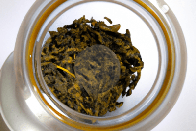 Frasco visto desde arriba con hojas de té oscuras y un disco compacto que ilustra como saber si un te esta caducado