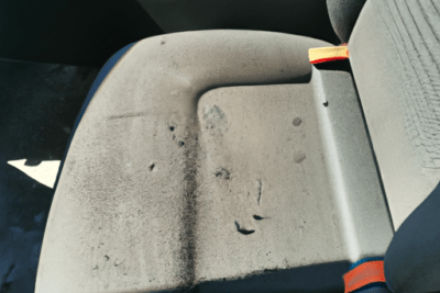Asiento de vehículo con manchas, desgaste y desgarros que muestra cómo detectar señales de caducidad: como saber si una silla de coche esta caducada