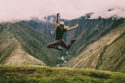 Persona saltando en un mirador de montaña con un valle profundo al fondo, inspira a configura aprovecha maximo apple watch zepp life
