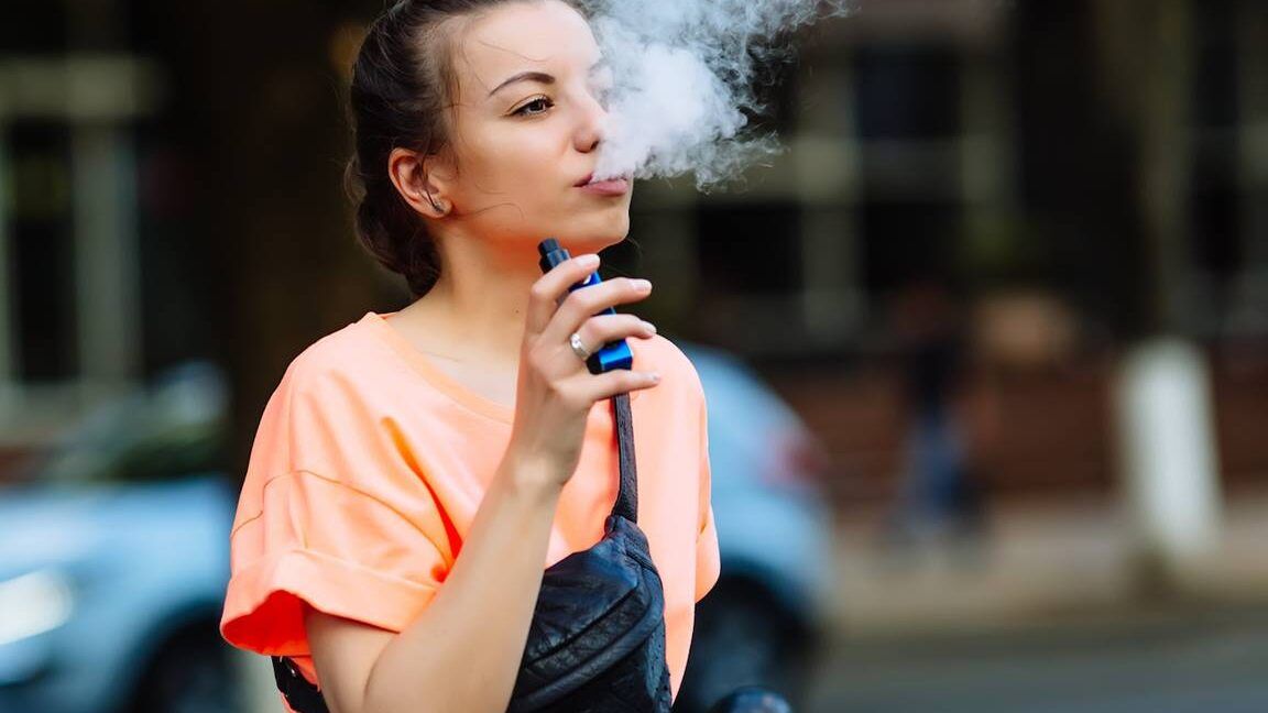 Joven exhalando vapor con un dispositivo electrónico, consecuencias de fumar vapeo a los 14 anos que deberias saber.