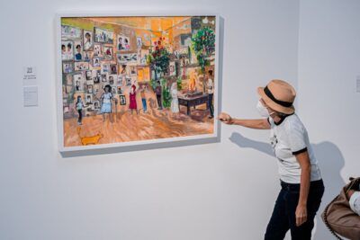 Visitantes con mascarilla observan una pintura de sala familiar que sugiere cual es el significado de echar lena al fuego