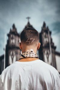 Joven de espaldas con diseño rasurado en la nuca frente a una iglesia explorando cual es significado numero