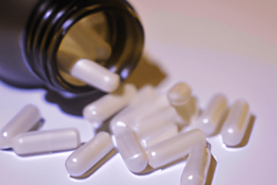 Frasco abierto con cápsulas blancas que ilustra cuanto tiempo sirve un medicamento despues de caducado