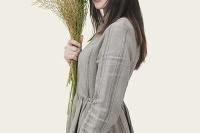 Mujer sonriente con vestido gris sosteniendo ramo de flores silvestres, descubre atractivos turisticos aguilar campoo