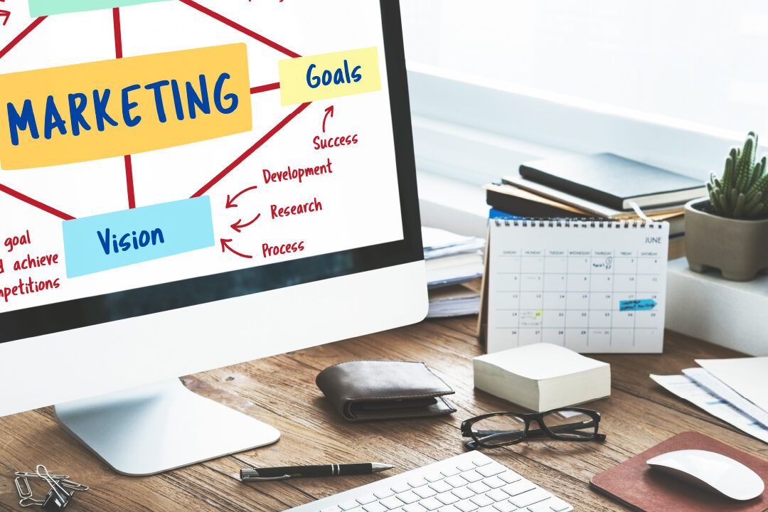 Escritorio con monitor mostrando un diagrama de marketing, calendario y materiales de oficina que sugiere descubre como usar el plan z de mercado libre y aumenta tus ventas