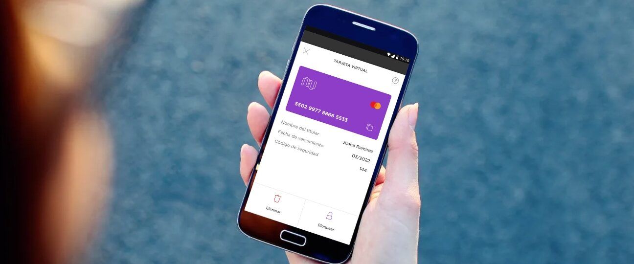 Mano sosteniendo un móvil con pantalla que muestra una tarjeta virtual púrpura y opciones de bloqueo y eliminación, descubre como usar la tarjeta virtual naranja x en simples pasos 1.