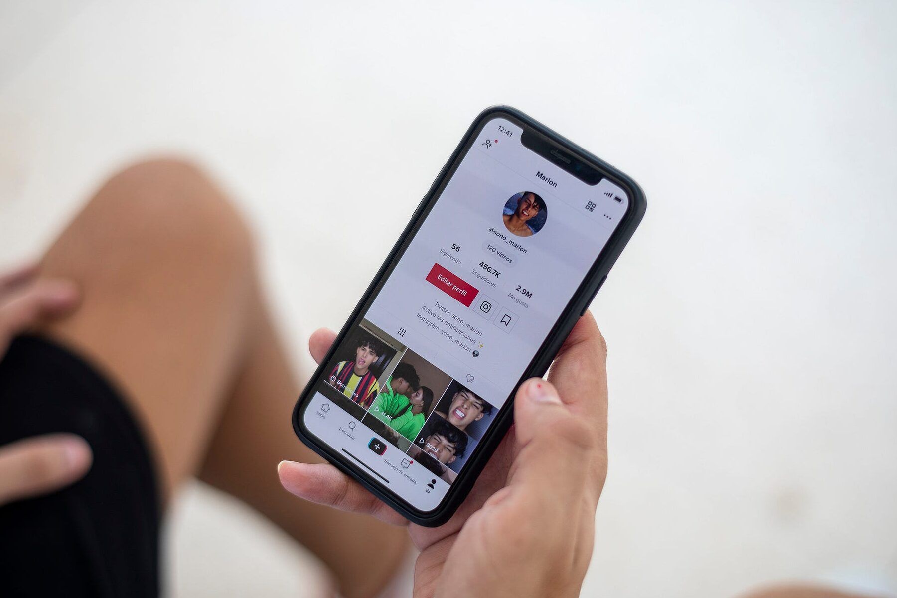 Persona sostiene un teléfono móvil con la aplicación TikTok abierta mostrando un perfil y miniaturas de videos, descubre como utilizar tik tok en cuba de manera facil y rapida 1.