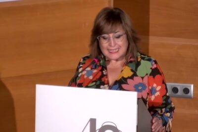 Mujer hablando en un atril durante una conferencia, descubre de que se alimentan las langostas y como influye en su ecosistema