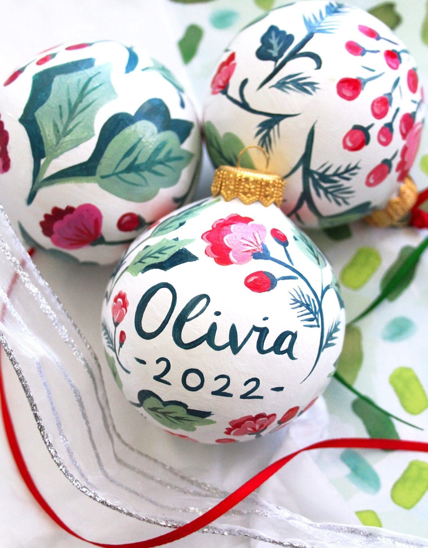 Bola navideña blanca pintada a mano con motivos florales, letras personalizadas y acabado dorado, descubre el nombre de la sorprendente bola de cristal con nieve dentro 1.