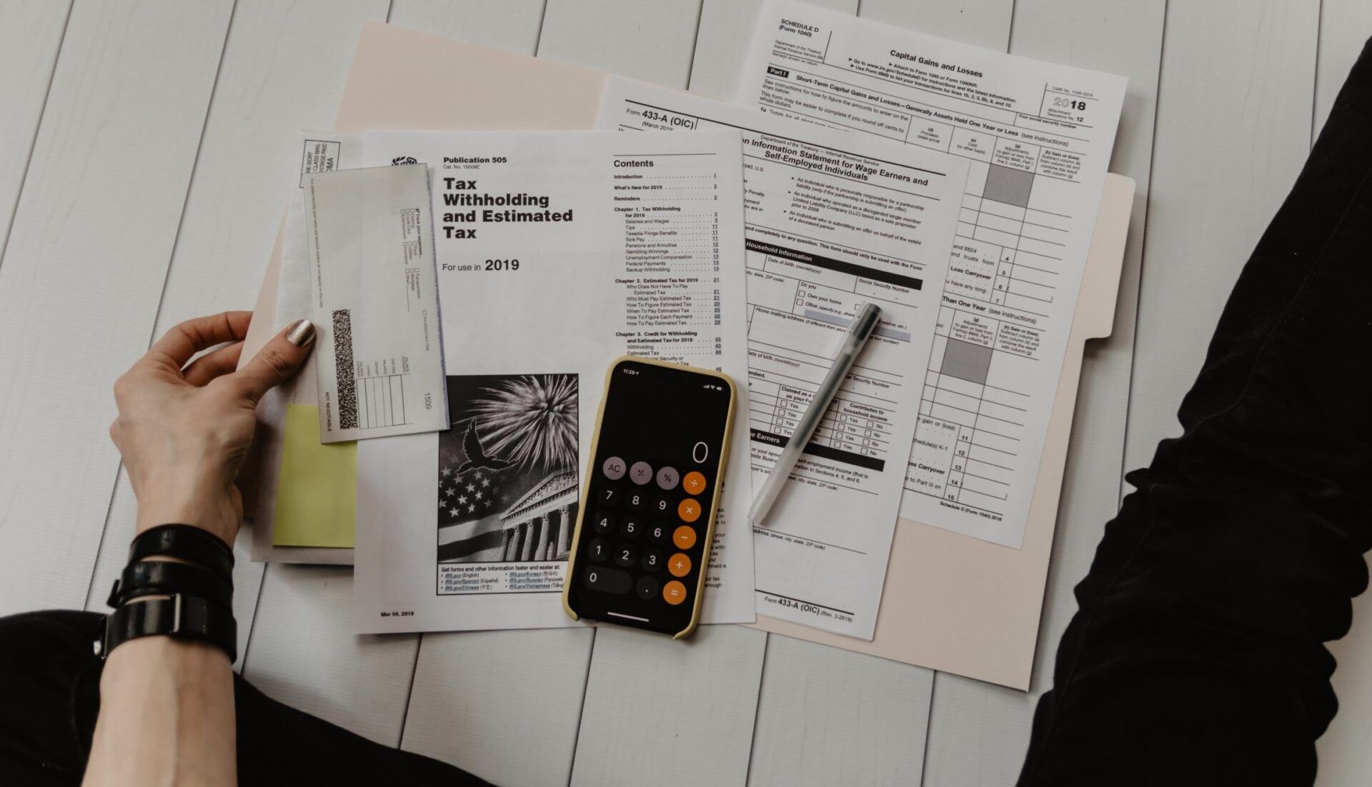 Persona revisando documentos fiscales, recibos y calculadora en teléfono para descubre el significado del albaran valorado y como afecta a tus compras 1