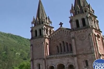 Iglesia románica con torres gemelas sobre colinas verdes, ideal para artículos que descubren la fascinante dieta de los cuervos y sus habitos alimenticios.