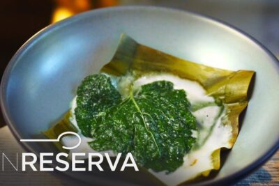 Plato en bol con hojas verdes sobre hoja de plátano y crema espumosa, descubre los sabores de la gastronomia italiana que comen los italianos
