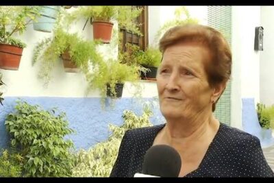 Mujer mayor siendo entrevistada frente a una fachada con macetas y plantas, descubre que comen los flamencos su dieta habitos alimenticios y curiosidades