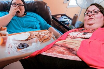Dos personas sentadas en un sofá con bandeja de pizza, donut y aperitivos, descubre que comen los linces dieta habitos alimenticios y mas