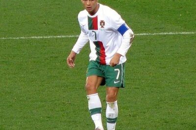 Jugador de fútbol con uniforme de Portugal controlando el balón en el césped, descubre significado influencia vida.