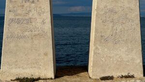 Dos pilares de piedra con grabados y motivos marinos frente al mar que invitan a descubre significado llevarse palma