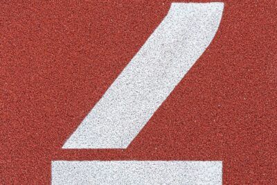 Marca blanca pintada sobre pista roja texturizada que invita a descubre significado numero dos