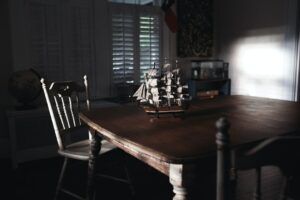 Maqueta de barco sobre una mesa de madera con sillas y luz tenue, descubre significado sonar perderse