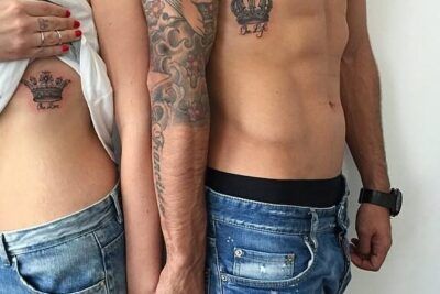 Dos personas de pie mostrando coronas a juego en el costado y el pecho, descubrir el poder y significado de un tatuaje de corona.