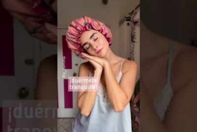 Mujer con dormir gorro rosa satinado y ojos cerrados simulando que duerme