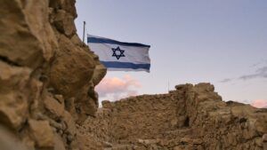 Ruinas de fortaleza en paisaje desértico con bandera israelí ondeando que evoca el asedio romano a masada