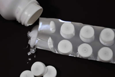 Bote abierto y blíster con tabletas esparcidas que ilustran el peligro de utilizar un medicamento caducado por mas de 6 meses.