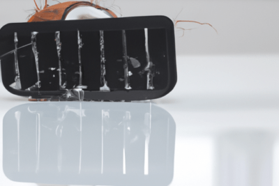 Primer plano de un cabezal negro con rejilla y gotas de agua reflejado sobre una superficie blanca, mostrando texturas y sugerente del problema de usar levadura fresca caducada causas y consecuencias