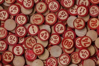 Montón de fichas de bingo de madera con borde rojo y números impresos, el sentido del numero explorando significado simbolismo.