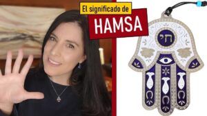 Mujer sonriente con la mano levantada junto a un colgante Hamsa, el significado de la mano de fatima origen y simbolismo 1