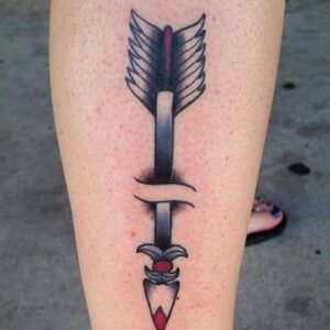 Tatuaje vertical en la pierna de una flecha con rotura central y acentos rojos que representa el significado de un tatuaje de flecha rota todo lo que debes saber 1