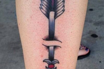 Tatuaje vertical en la pierna de una flecha con rotura central y acentos rojos que representa el significado de un tatuaje de flecha rota todo lo que debes saber 1