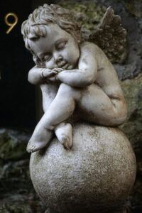 Estatua de querubín dormido sobre una esfera que evoca el significado del numero simbolismo y misterios