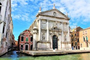 Fachada monumental junto al canal veneciano iluminada por el sol que evoca el simbolismo del numero significado y misterios.