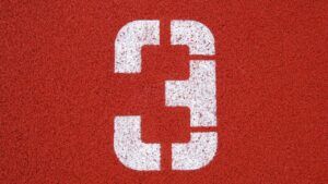 Número 3 blanco pintado sobre una superficie roja de pista deportiva que evoca el simbolismo del numero significado y misterios revelados.