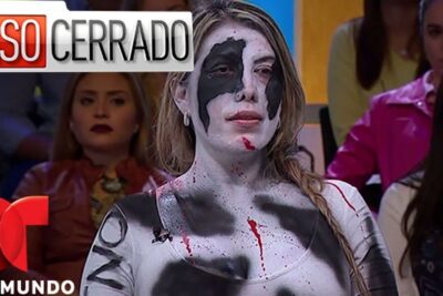 Mujer con pintura corporal blanca y negra y salpicaduras rojas en caso televisivo frente a la audiencia.