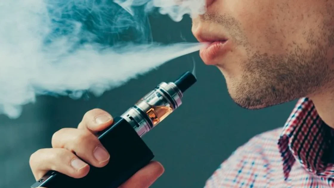 Primer plano de una persona exhalando vapor con un cigarrillo electrónico, es seguro fumar vape despues de sacarse una muela descubre la respuesta aqui