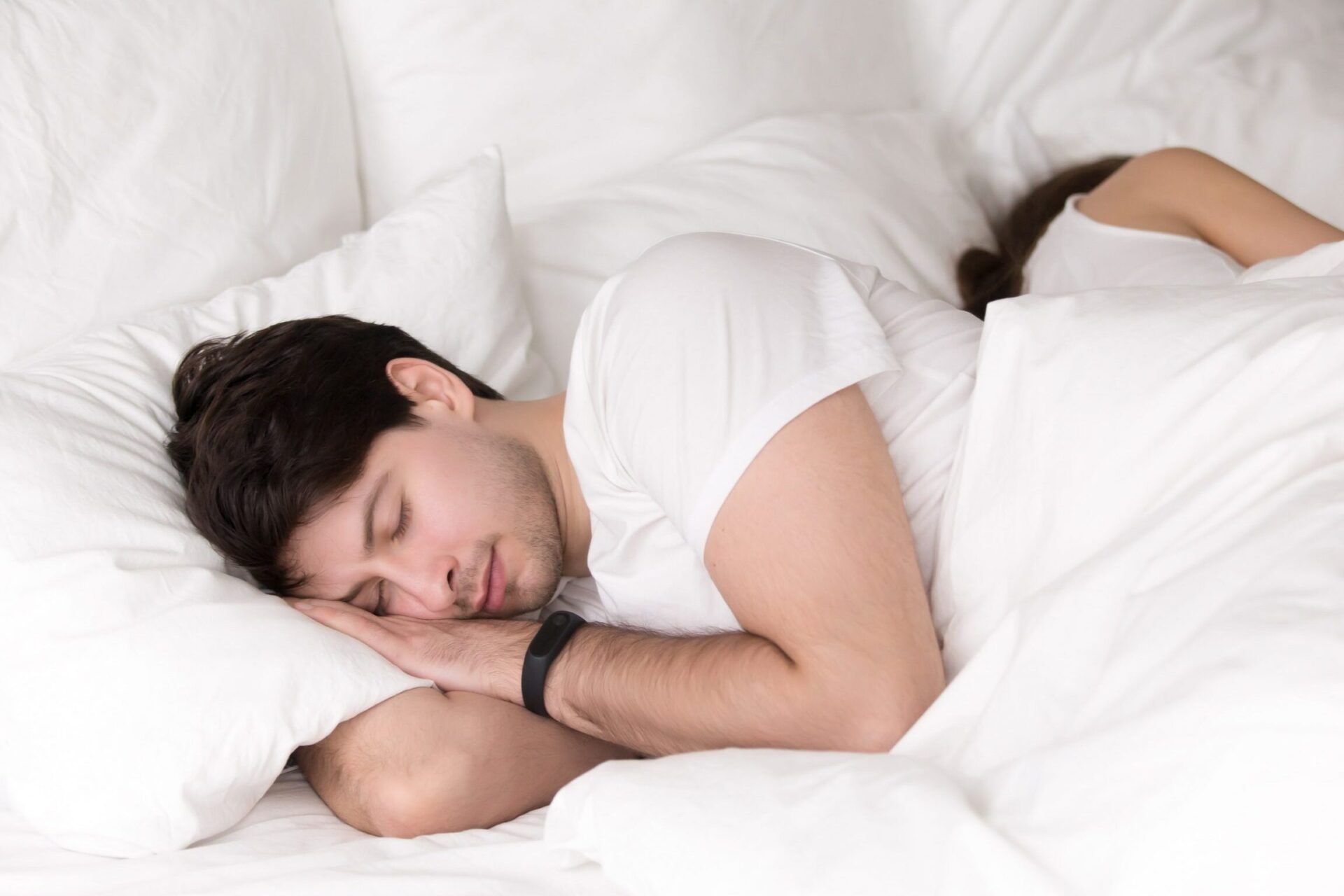 Hombre joven durmiendo de lado sobre almohadas y sábanas blancas, imagen para escupiste sangre descubre que significa y cuando debes preocuparte